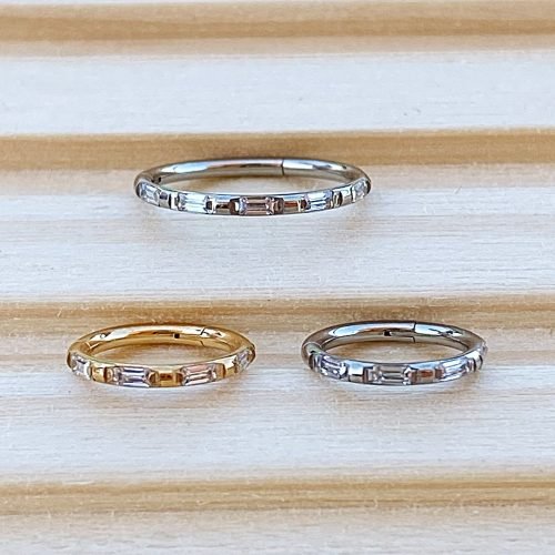 Alternative view of Aro clicker de titanio con baño de oro y zirconias talla baguette